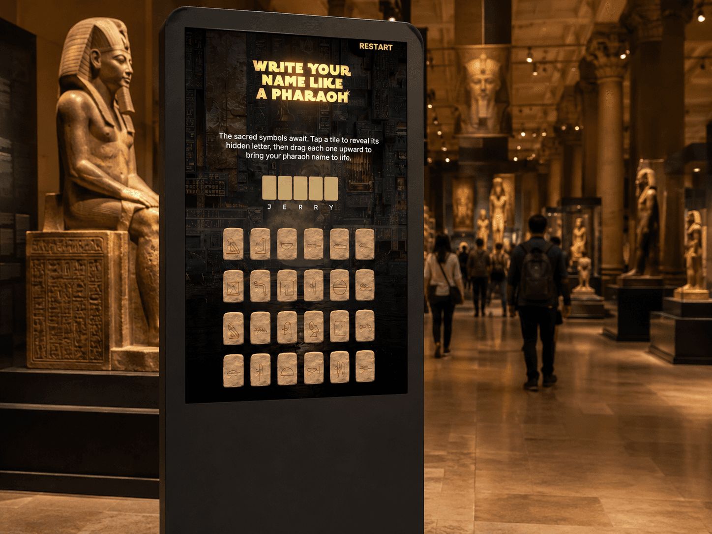 The hieroglyph tile grid on the museum touchscreen, with a visitor name being spelled out letter by letter